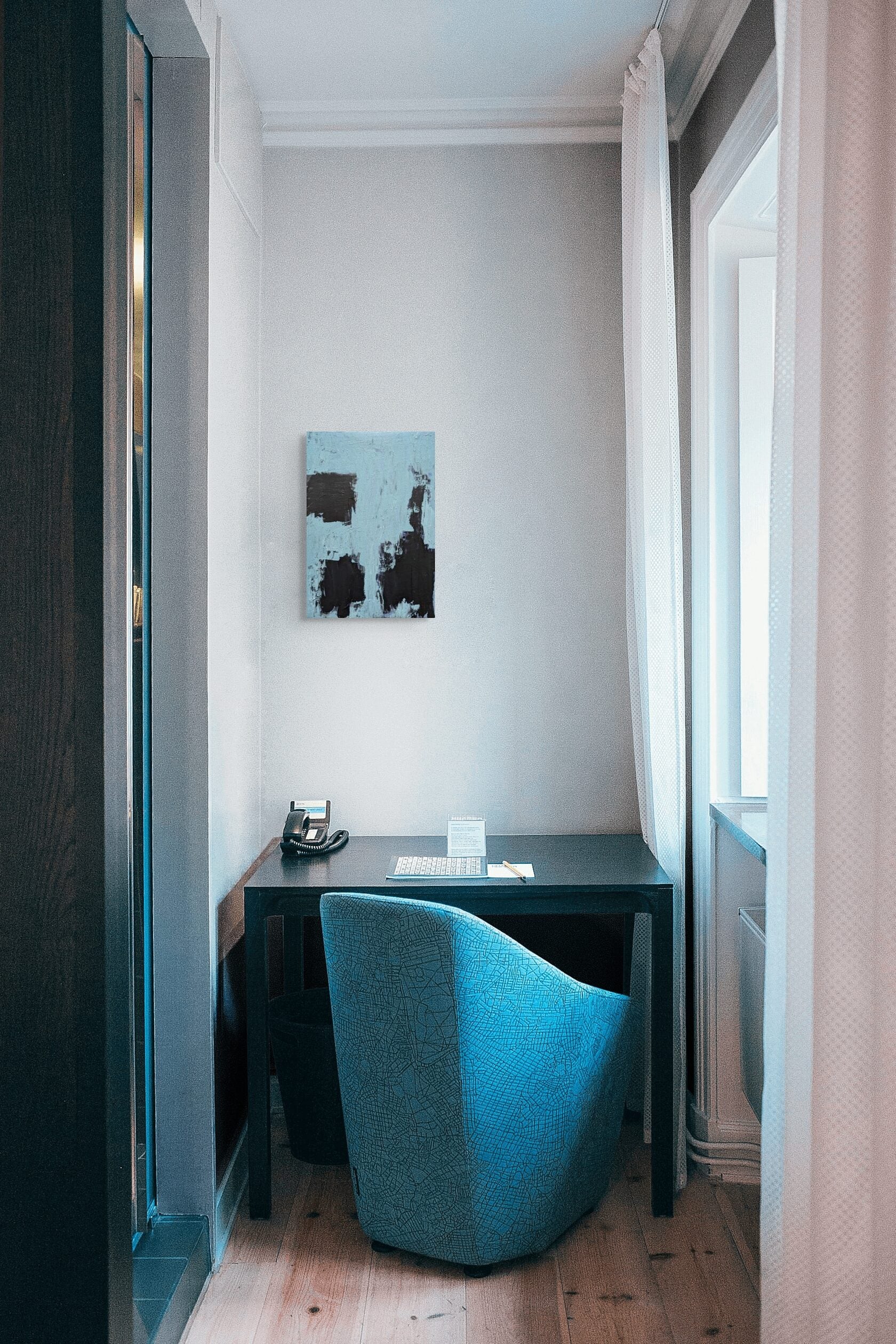 a cozy corner of a room with a desk, chair, and a painting on the wall.