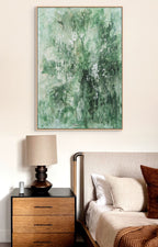 a bedroom with a large abstract painting hanging on the wall above a wooden nightstand with a lamp. The painting has a green and white color scheme, creating a serene and calming atmosphere in the room.