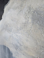 The image is a close-up of a textured surface, possibly a wall or a piece of fabric, with a predominantly white and gray color palette. The surface appears to be made of a material that has a rough, textured appearance, possibly with some areas of darker or lighter coloration. The image does not contain any discernible objects or actions, and there are no specific actions or movements depicted. The focus is on the texture and color of the surface.