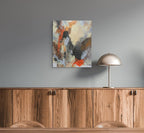 Abstract painting on a gray wall above wooden cabinets with a metallic lamp.
