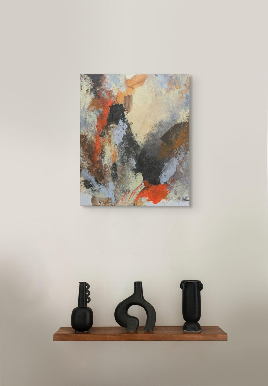 Abstract painting on a wall above a wooden shelf with three black vases.