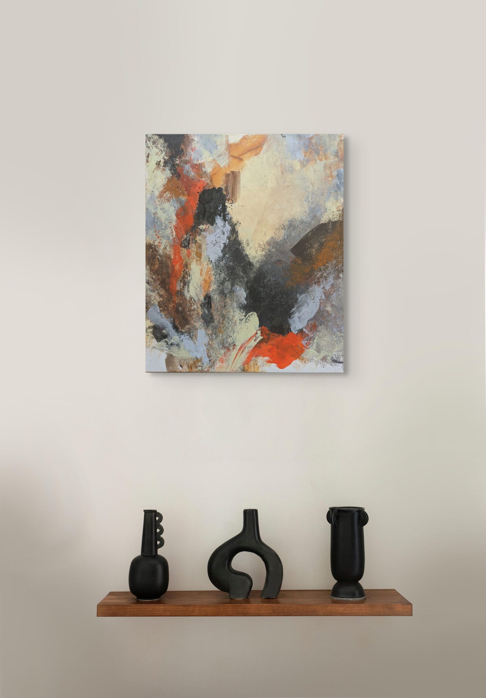 Abstract painting on a wall above a wooden shelf with three black vases.