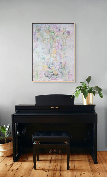a Yamaha piano with a black frame, a black stool, and a potted plant on the floor next to the piano. The piano is positioned in front of a gray wall, and a framed abstract painting is hanging above it.
