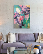 Colorful abstract painting on a wall above a gray sofa in a living room.