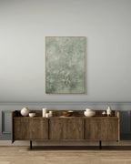 Wooden sideboard with decorative items against a gray wall with a framed abstract painting.