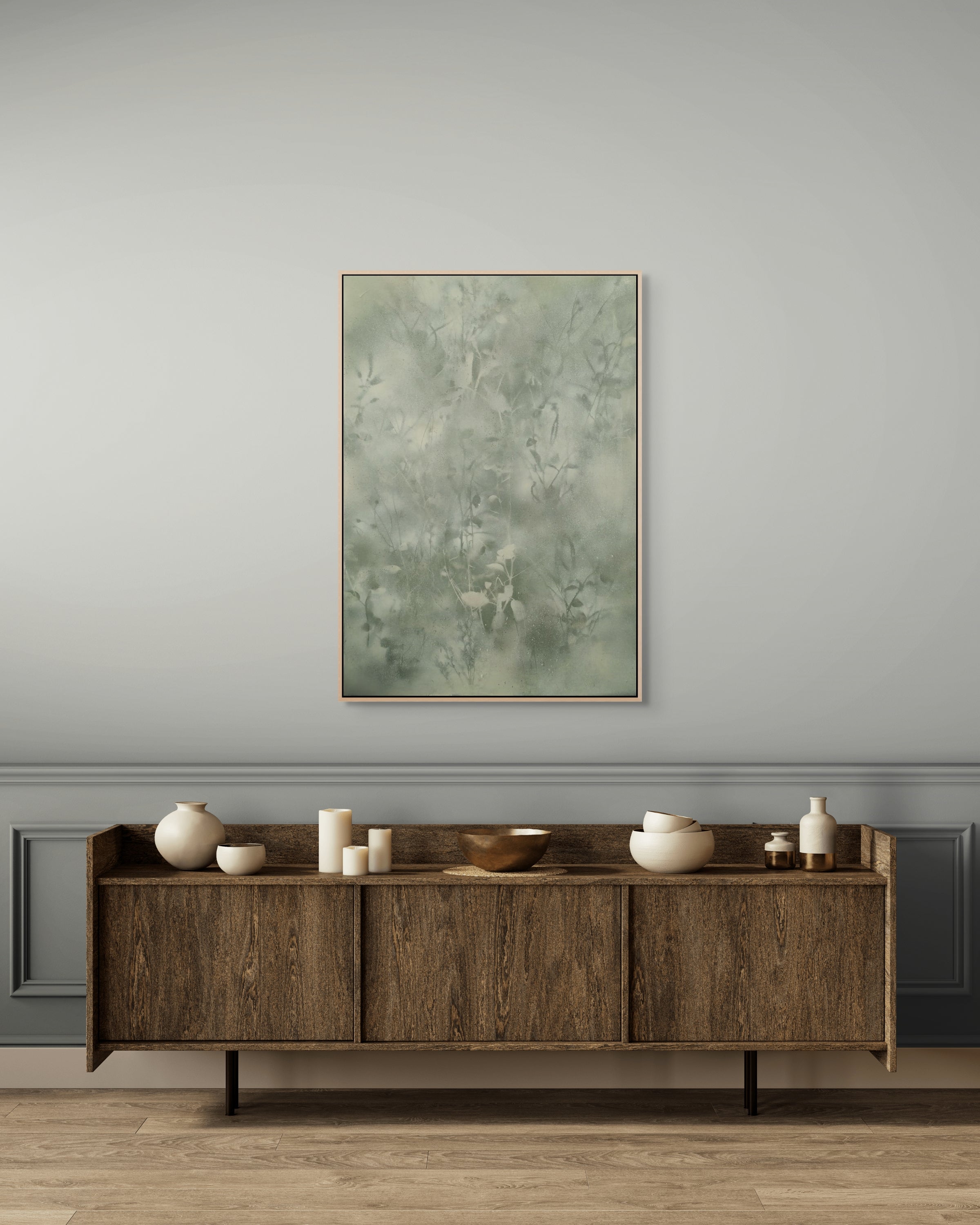 Wooden sideboard with decorative items against a gray wall with a framed abstract painting.