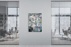 Abstract painting on a wall in an office setting with glass walls and chairs.