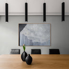 Modern office interior with a wooden desk, black chairs, and abstract art on the wall.