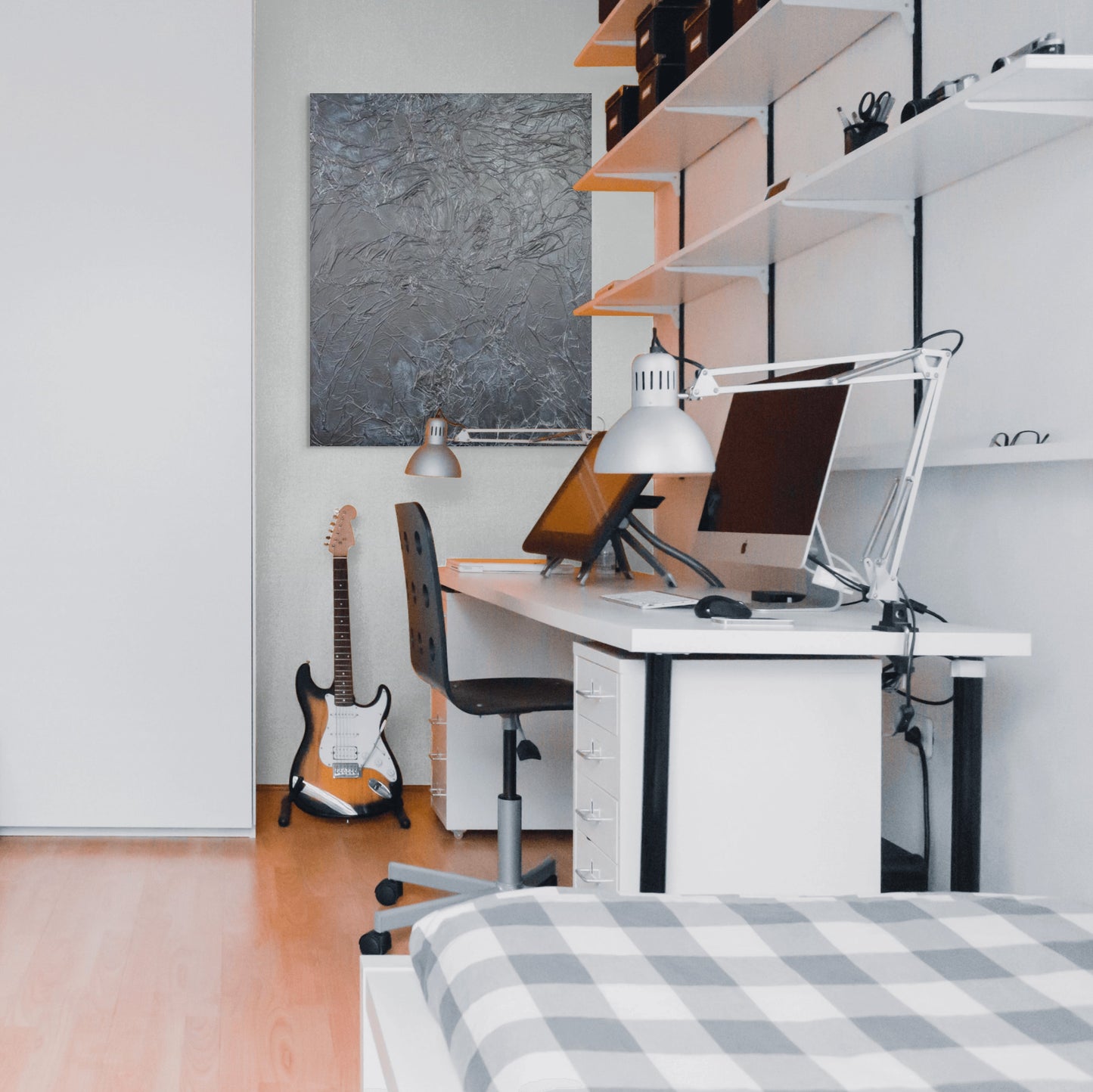 a modern, minimalist bedroom with a white desk, a guitar, and a bed.