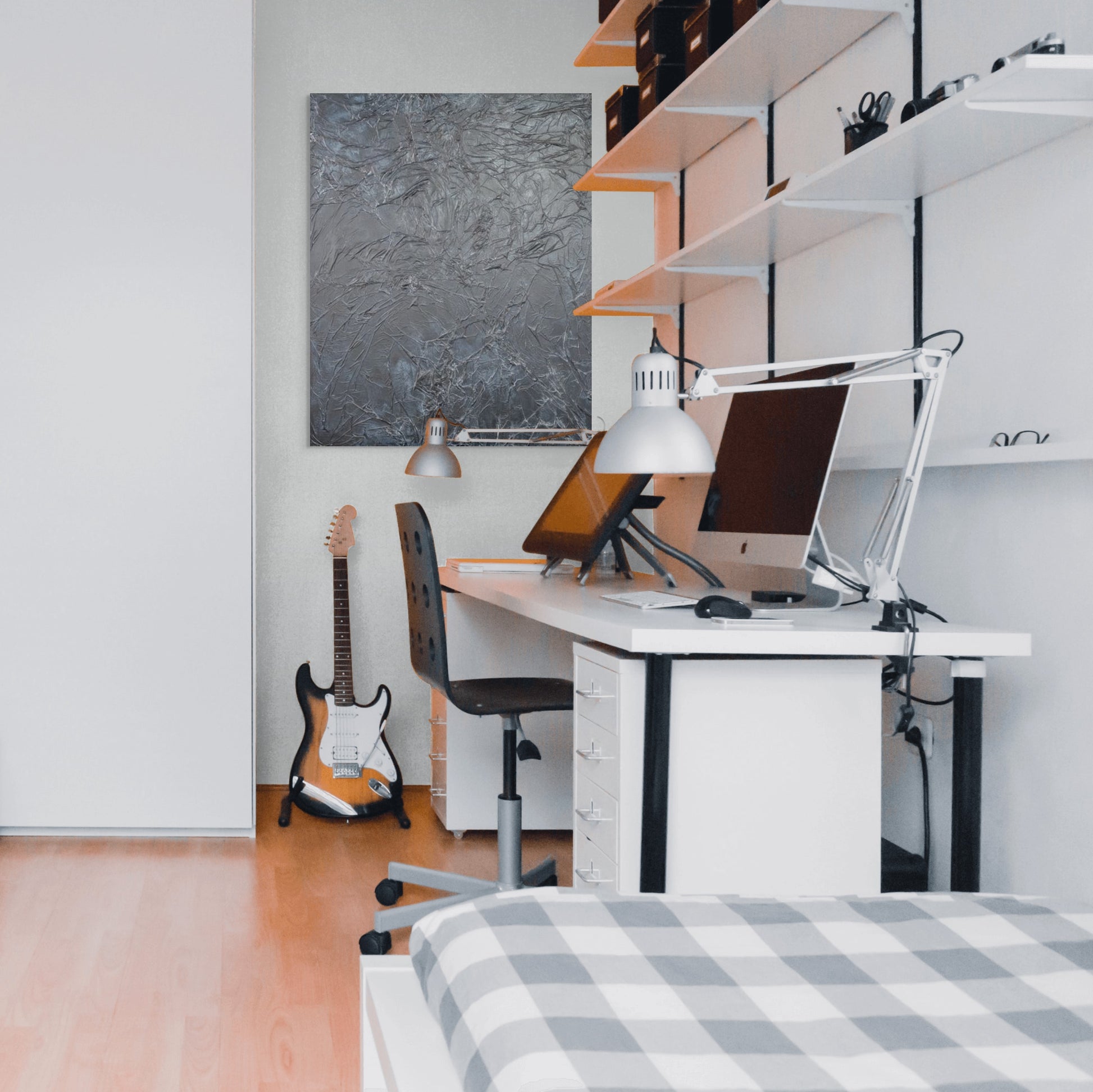 a modern, minimalist bedroom with a white desk, a guitar, and a bed.